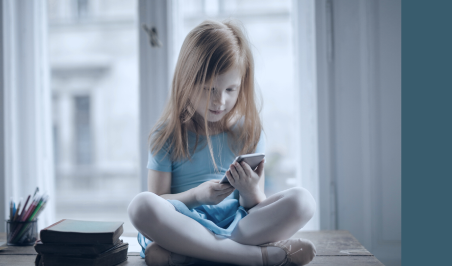 Bambina con le gambe incrociate usa uno smartphone